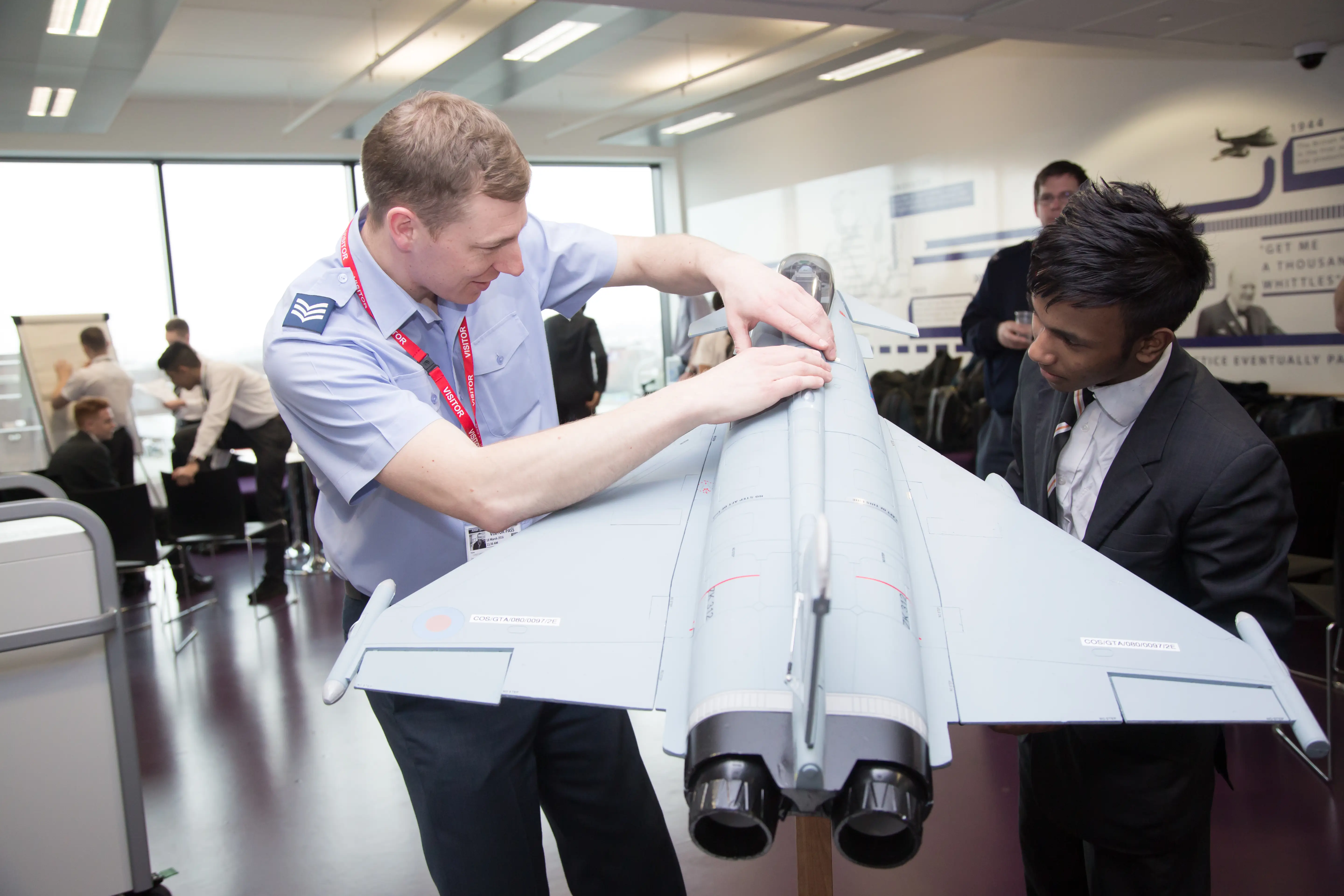 An RAF engineer showing a student a scale model fighter jet