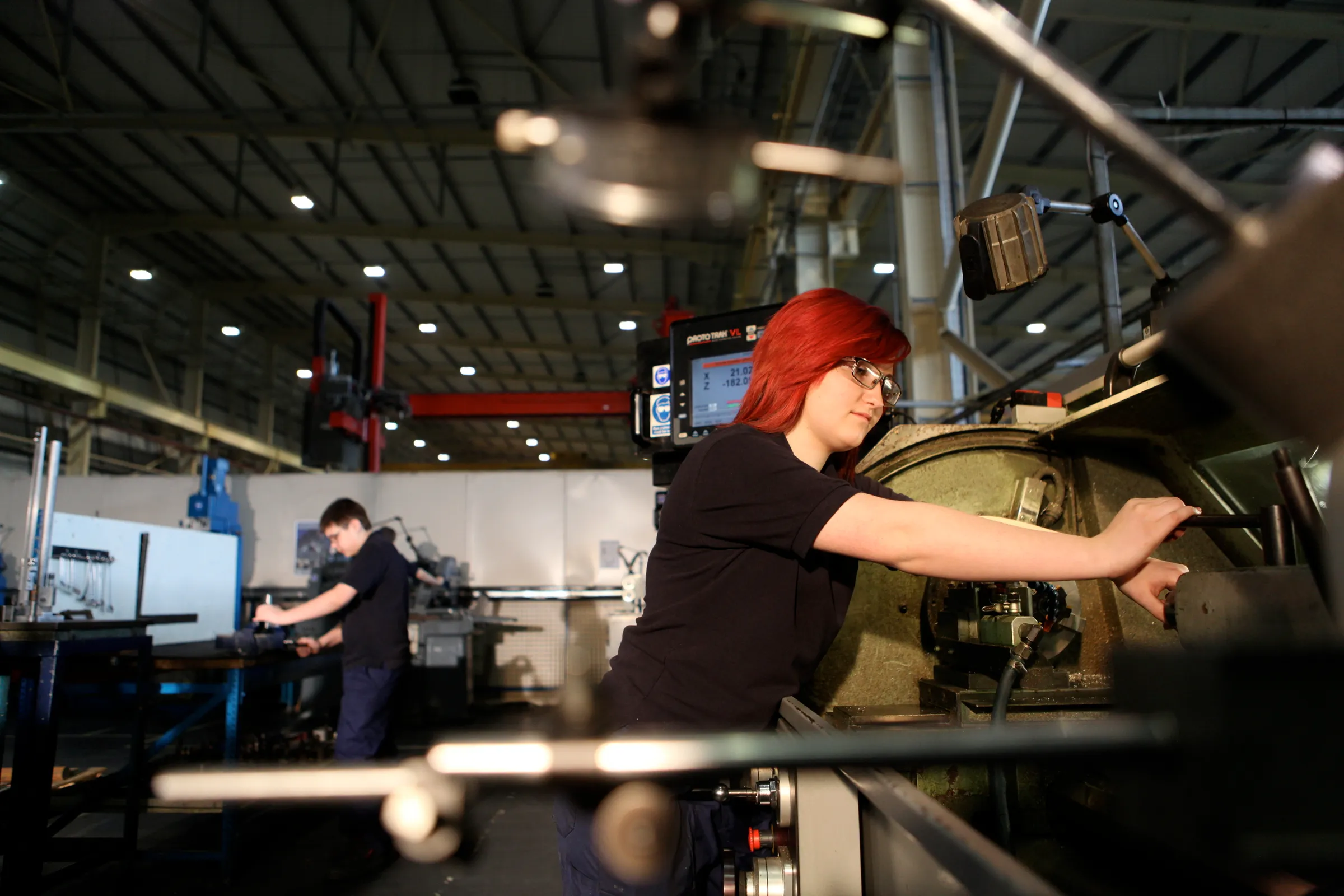 Student operating a CNC lathe in an engineering workshop