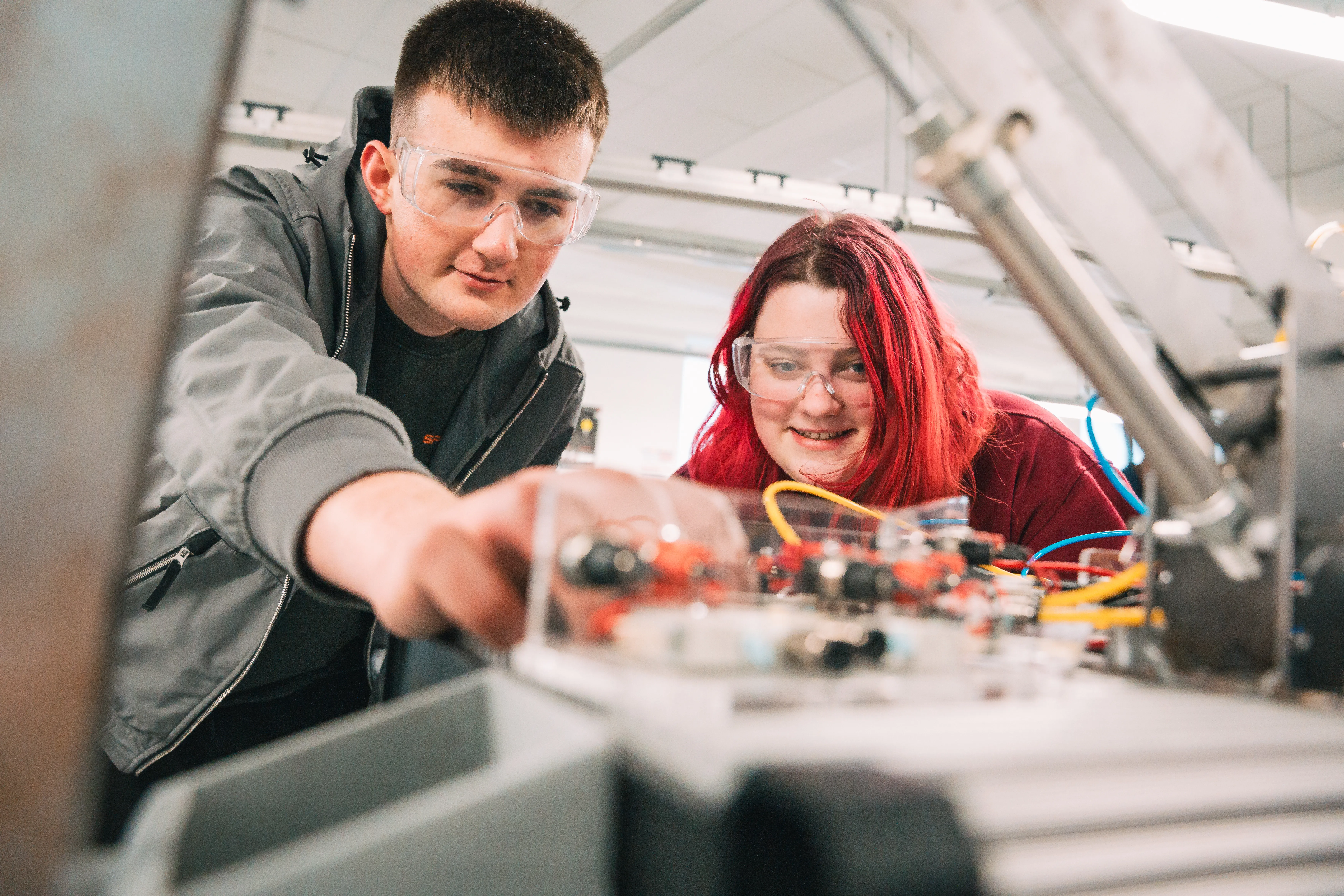 Two students wiring a circuit board together on a live project
