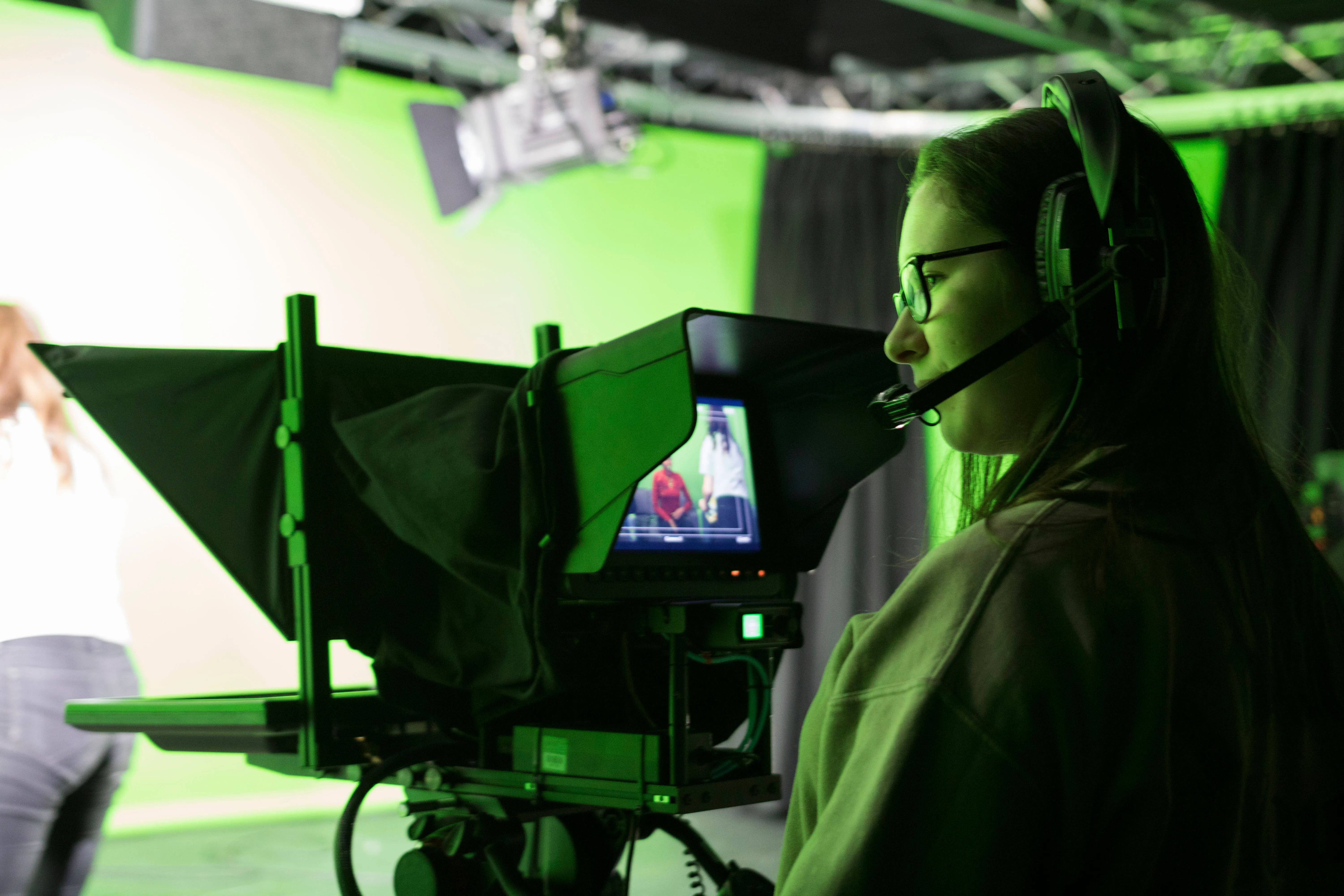 Student directing a broadcast from behind a studio teleprompter